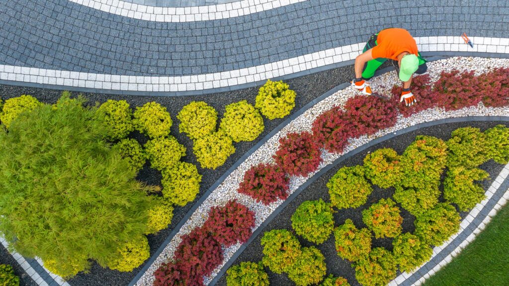 Arial photo of a gardener working on backyard landscaping with rocks, bricks and plants