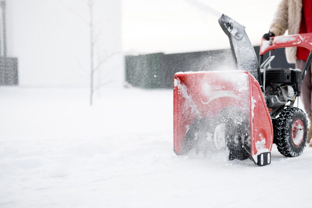 person running a snow blower machine on a sidewalk